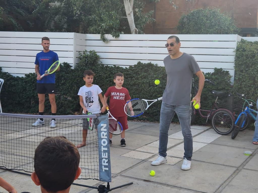 Adult man teaches children how to play tennis